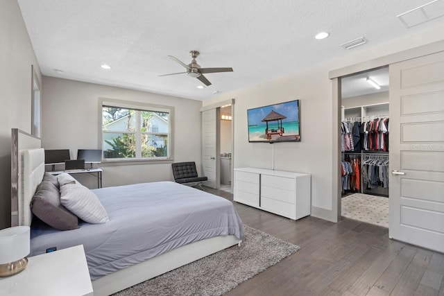 bedroom with ceiling fan, a spacious closet, dark hardwood / wood-style flooring, a textured ceiling, and a closet