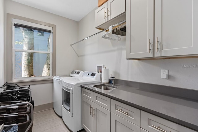 laundry room with cabinets, light tile patterned floors, sink, and washing machine and dryer