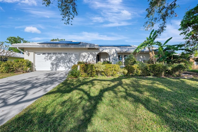 ranch-style house with a garage, a front lawn, and solar panels