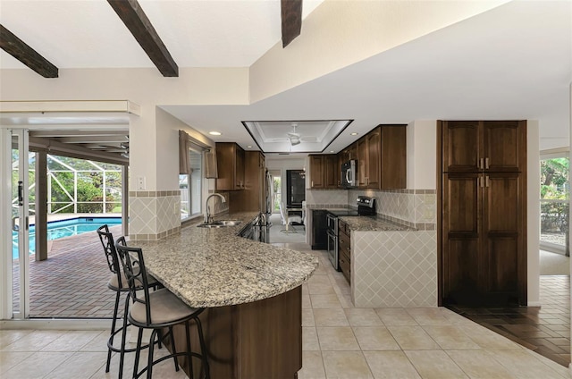 kitchen with a breakfast bar, sink, appliances with stainless steel finishes, kitchen peninsula, and backsplash