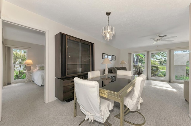 carpeted dining area with ceiling fan with notable chandelier and a textured ceiling