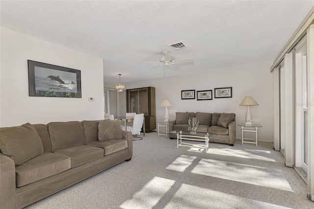 living room featuring ceiling fan with notable chandelier and light carpet