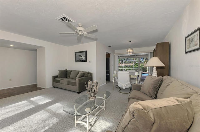 living room featuring ceiling fan with notable chandelier, light colored carpet, and a textured ceiling