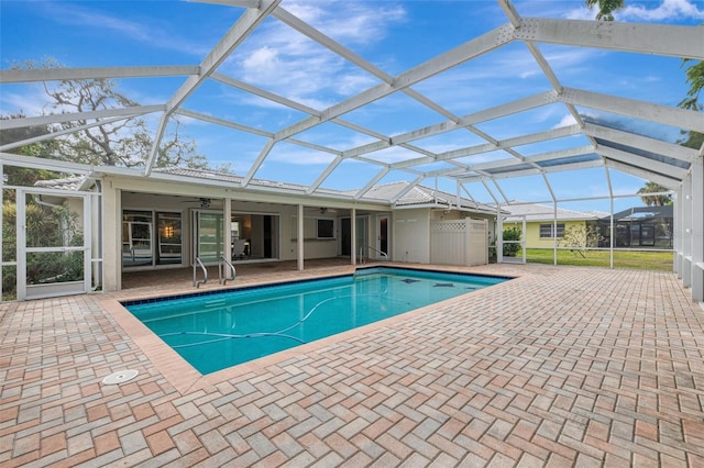 view of swimming pool with ceiling fan, glass enclosure, and a patio area