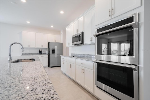 kitchen featuring sink, light tile patterned flooring, light stone counters, white cabinetry, and stainless steel appliances