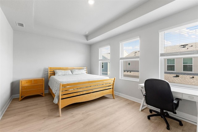 bedroom featuring a tray ceiling and light hardwood / wood-style floors