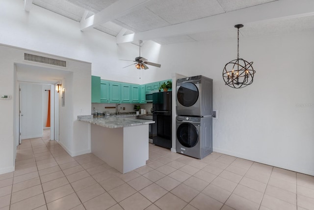 kitchen featuring kitchen peninsula, black refrigerator, light tile patterned floors, high vaulted ceiling, and stacked washer / drying machine