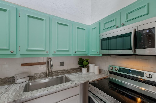 kitchen featuring decorative backsplash, green cabinets, sink, and appliances with stainless steel finishes