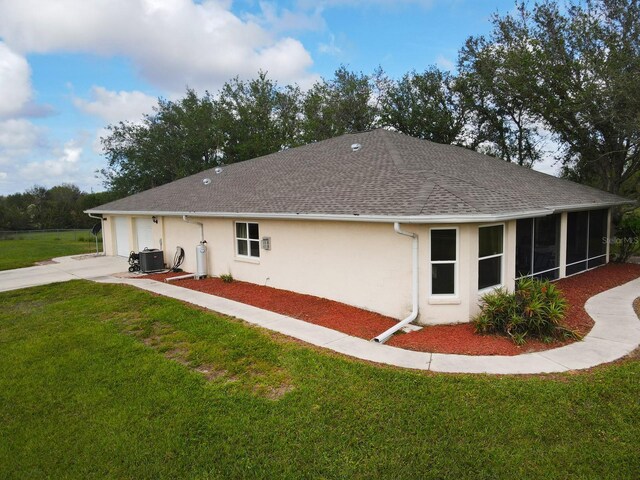31730 Clay Gully Rd, Myakka City, FL 34251 - back of property with stucco siding, a lawn, concrete driveway, central AC, and an attached garage