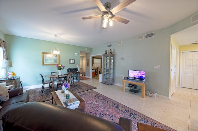 tiled living room featuring ceiling fan with notable chandelier