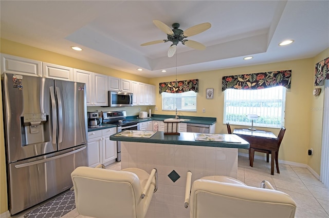 kitchen with ceiling fan, white cabinetry, appliances with stainless steel finishes, and a tray ceiling