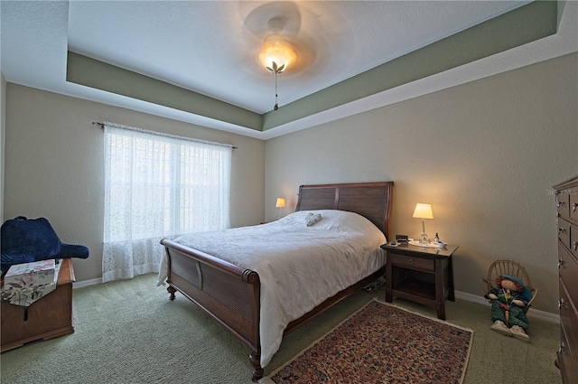 bedroom with a raised ceiling, ceiling fan, and carpet floors