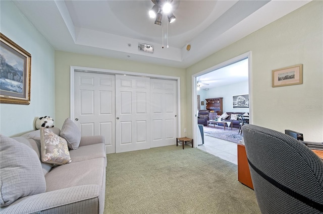 carpeted office featuring a tray ceiling and ceiling fan