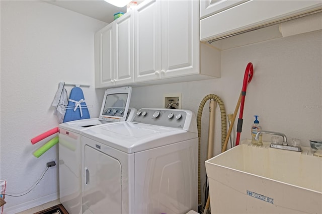 clothes washing area featuring sink, cabinets, and independent washer and dryer