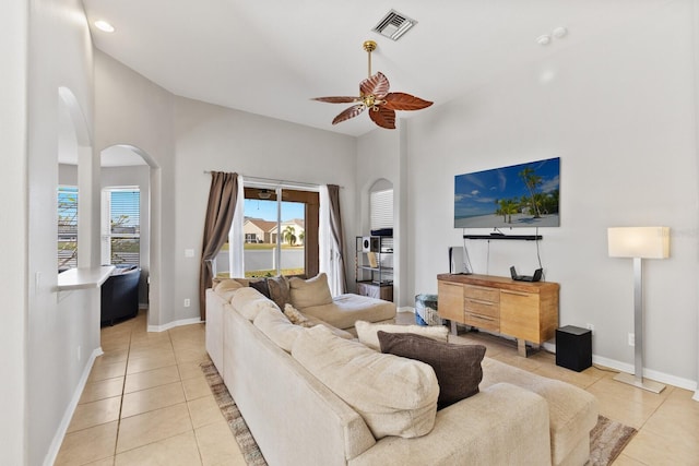 living room with ceiling fan, light tile patterned flooring, and a towering ceiling