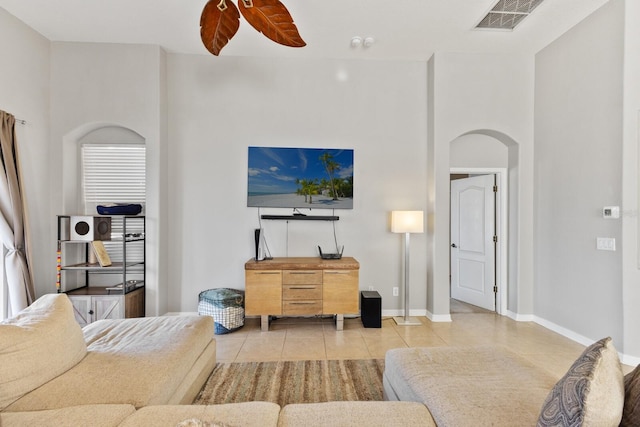 living room featuring light tile patterned floors, a towering ceiling, and ceiling fan