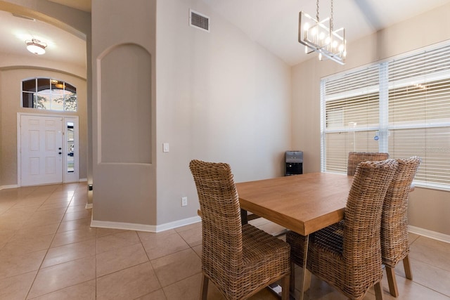 tiled dining area with a notable chandelier and vaulted ceiling