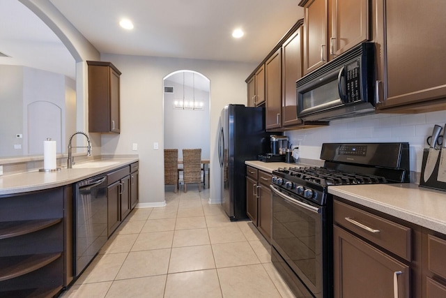 kitchen featuring light tile patterned flooring, dark brown cabinets, sink, and black appliances