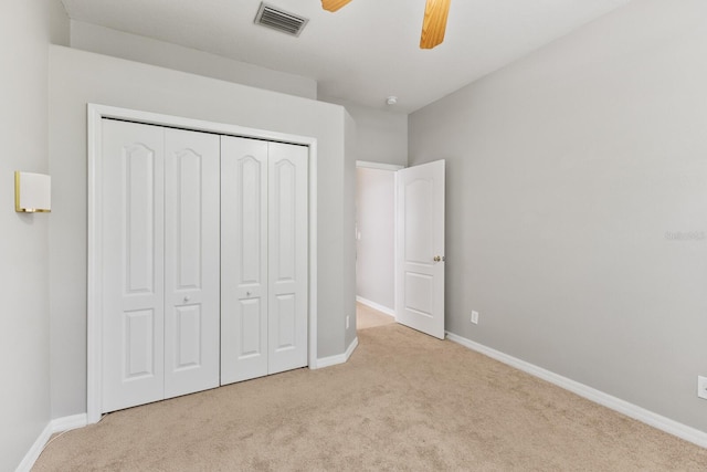 unfurnished bedroom featuring ceiling fan, light carpet, and a closet