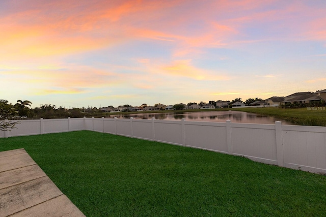 yard at dusk featuring a water view