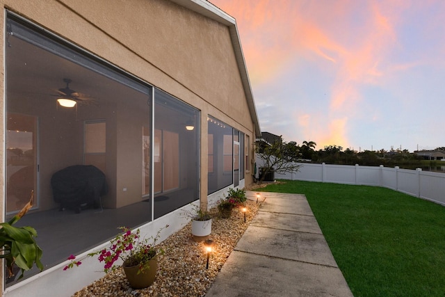 yard at dusk featuring a sunroom