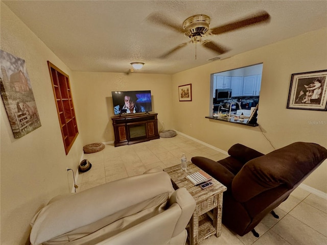 living room with a textured ceiling, ceiling fan, and light tile patterned flooring