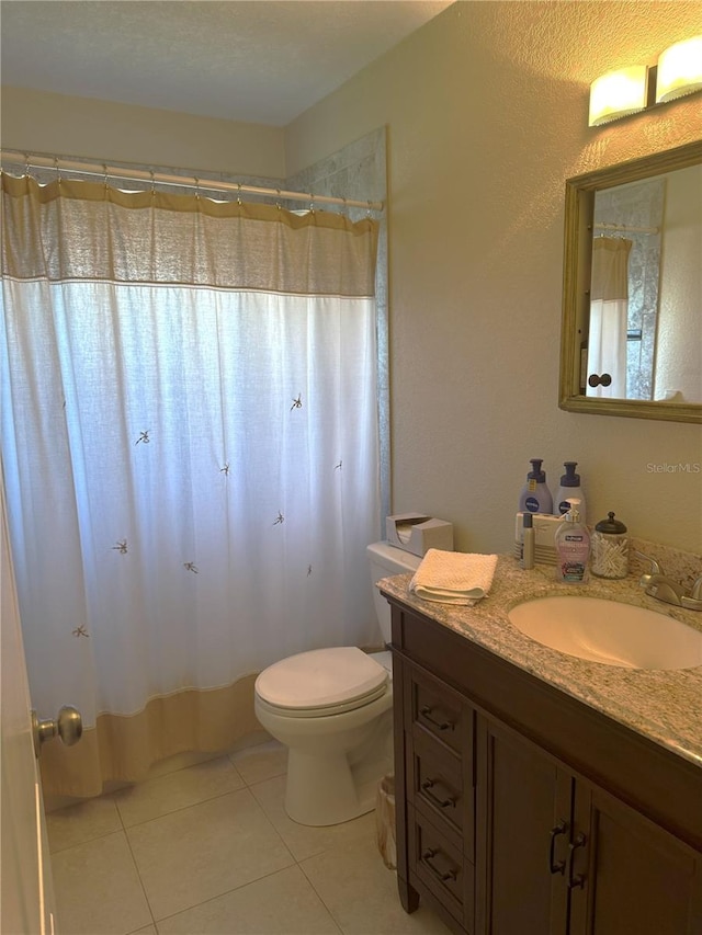 bathroom featuring tile patterned flooring, vanity, toilet, and curtained shower