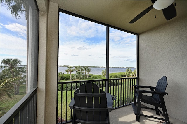 sunroom featuring ceiling fan and a water view