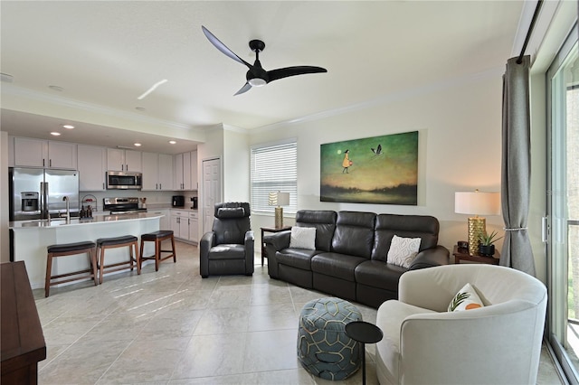 tiled living room featuring sink, plenty of natural light, crown molding, and ceiling fan