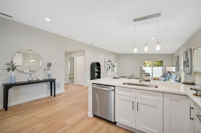 kitchen featuring stainless steel dishwasher, sink, pendant lighting, white cabinets, and light hardwood / wood-style floors