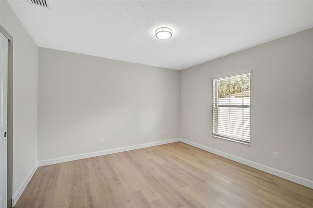 empty room with light hardwood / wood-style flooring and a textured ceiling