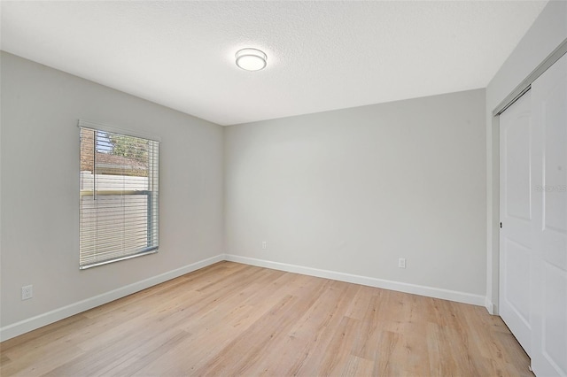 spare room with a textured ceiling and light hardwood / wood-style floors