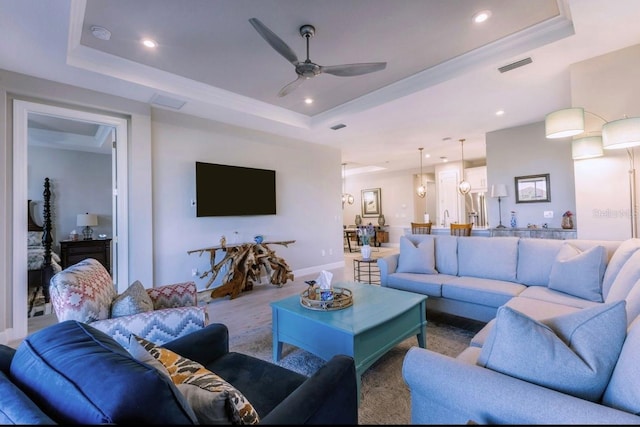 living room featuring ceiling fan and a raised ceiling