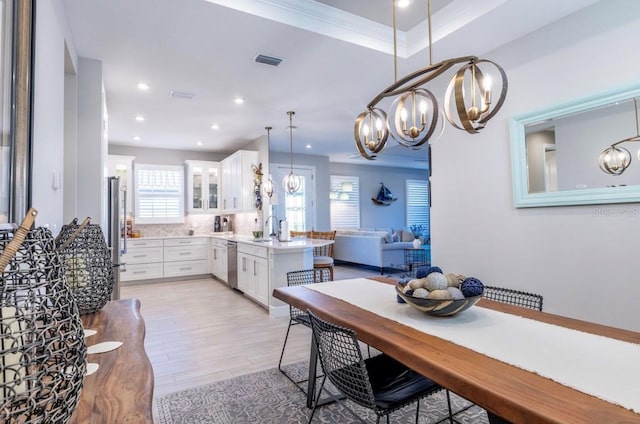 kitchen with appliances with stainless steel finishes, light wood-type flooring, white cabinetry, and a healthy amount of sunlight