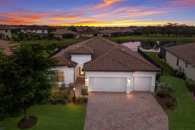 13627 American Prairie Pl, Lakewood Ranch, FL 34211 - mediterranean / spanish-style home featuring an attached garage, a water view, driveway, stucco siding, and a residential view