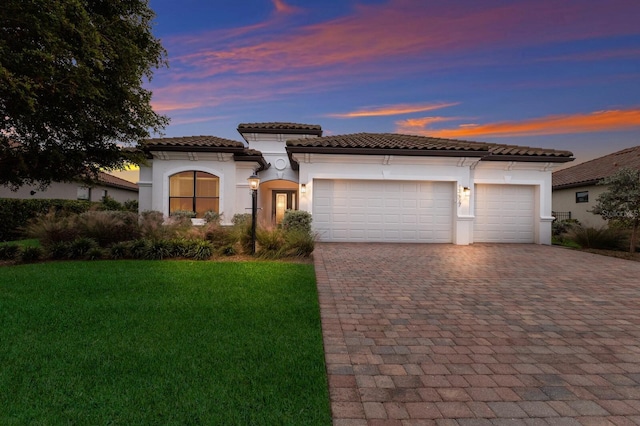 13627 American Prairie Pl, Lakewood Ranch, FL 34211 - mediterranean / spanish home featuring decorative driveway, stucco siding, a garage, a tile roof, and a yard