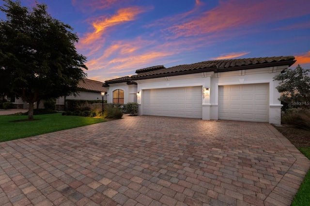 13627 American Prairie Pl, Lakewood Ranch, FL 34211 - mediterranean / spanish house with decorative driveway, an attached garage, stucco siding, a tile roof, and a front lawn