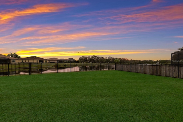 yard at dusk featuring a water view