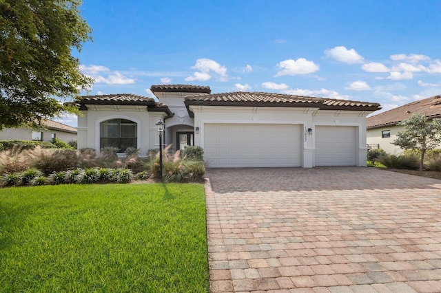 13627 American Prairie Pl, Lakewood Ranch, FL 34211 - mediterranean / spanish-style home with decorative driveway, stucco siding, an attached garage, and a front lawn