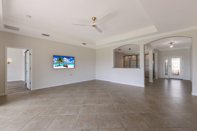 13627 American Prairie Pl, Lakewood Ranch, FL 34211 - unfurnished living room with a tray ceiling, a ceiling fan, arched walkways, crown molding, and tile patterned floors