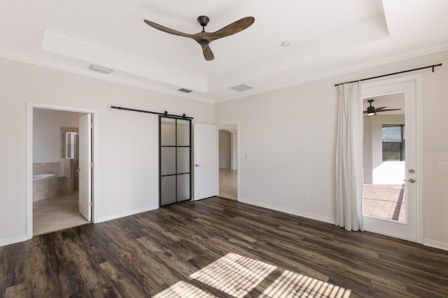 unfurnished bedroom featuring dark hardwood / wood-style flooring, connected bathroom, a tray ceiling, and ceiling fan