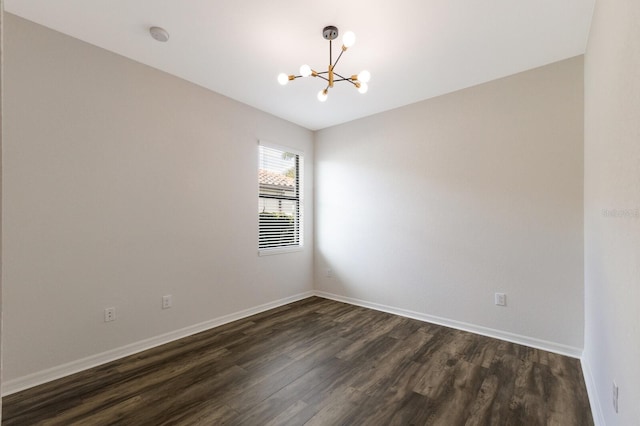 spare room featuring dark wood-type flooring and an inviting chandelier