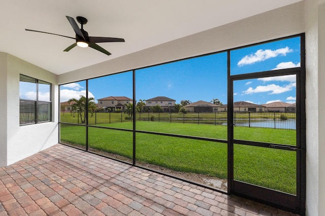 unfurnished sunroom featuring ceiling fan and a water view