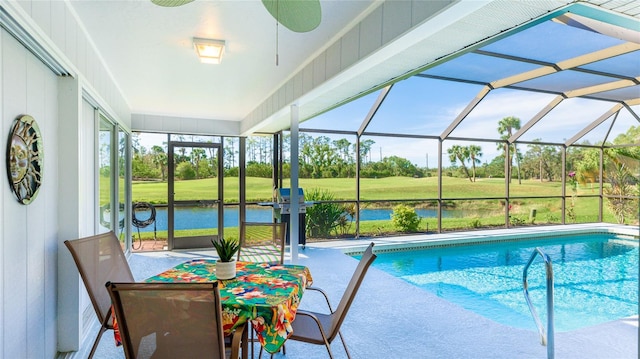 view of swimming pool with ceiling fan, a water view, glass enclosure, a patio area, and a yard