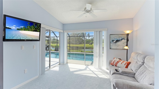 carpeted living room featuring vaulted ceiling, ceiling fan, a water view, and a textured ceiling