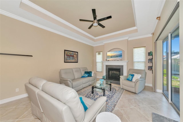 tiled living room with a raised ceiling, ceiling fan, and ornamental molding