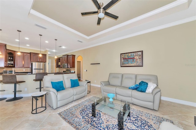 tiled living room featuring a tray ceiling, ceiling fan, and ornamental molding