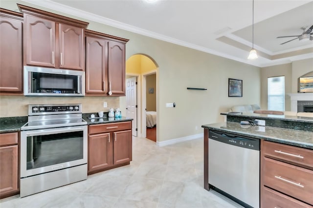 kitchen featuring dark stone counters, ornamental molding, stainless steel appliances, ceiling fan, and pendant lighting