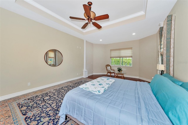 bedroom with a tray ceiling, ornate columns, ceiling fan, and crown molding