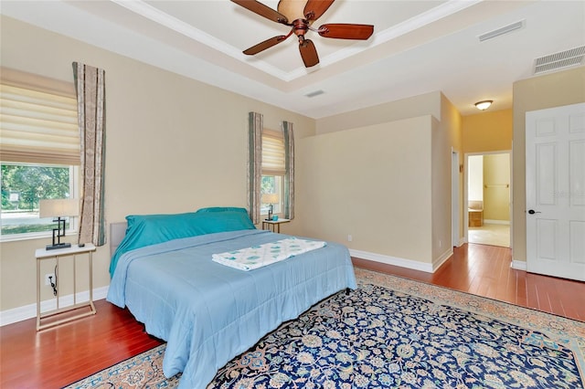 bedroom featuring hardwood / wood-style floors, ceiling fan, and a raised ceiling